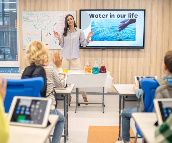 woman-standing-children-sitting-desks_259150-60228